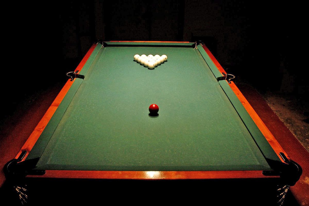 A Russian pyramid set racked at the foot of the table, the object balls white