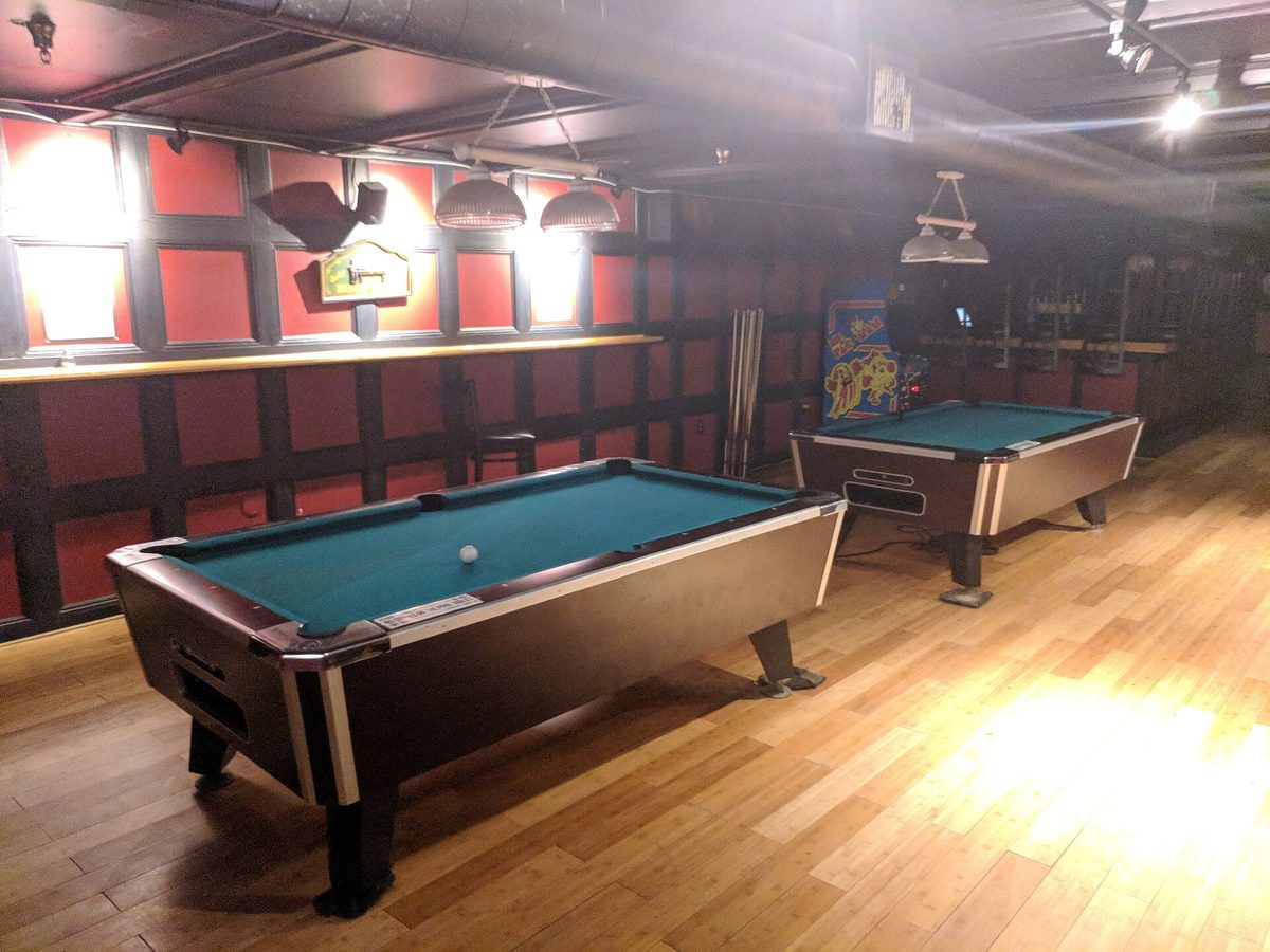 A home pool table set up for play, balls racked and cue ready
